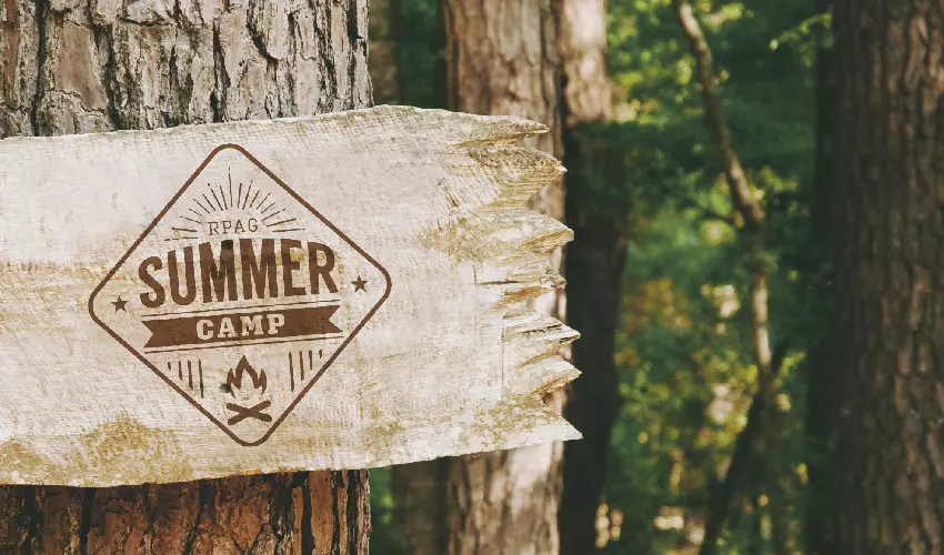 Summer camp sign nailed to a tree in a forest