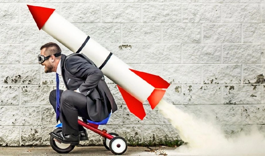 Man on a tricycle with a rocket strapped to his back